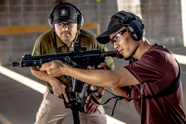 man teaching another man rifle skills